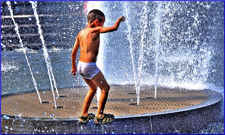 child playing in public fountain