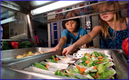 [children reaching for salads at school cafeteria]