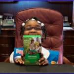 little girl poses with box of Girl Scout cookies