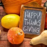 46177351 - happy thanksgiving - white chalk handwriting on a small blackboard surrounded by pumpkin and winter squash