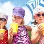 three-girls-on-beach-drinking-juice