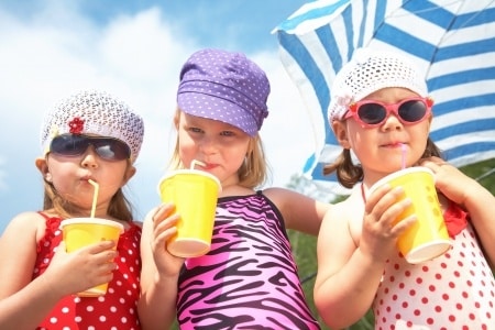three-girls-on-beach-drinking-juice