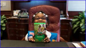 little girl poses with box of Girl Scout cookies